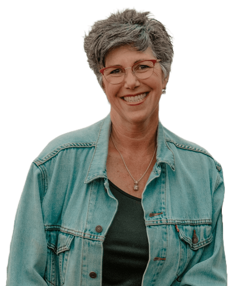 Smiling woman with short hair wearing glasses, a denim jacket, and a dark top.